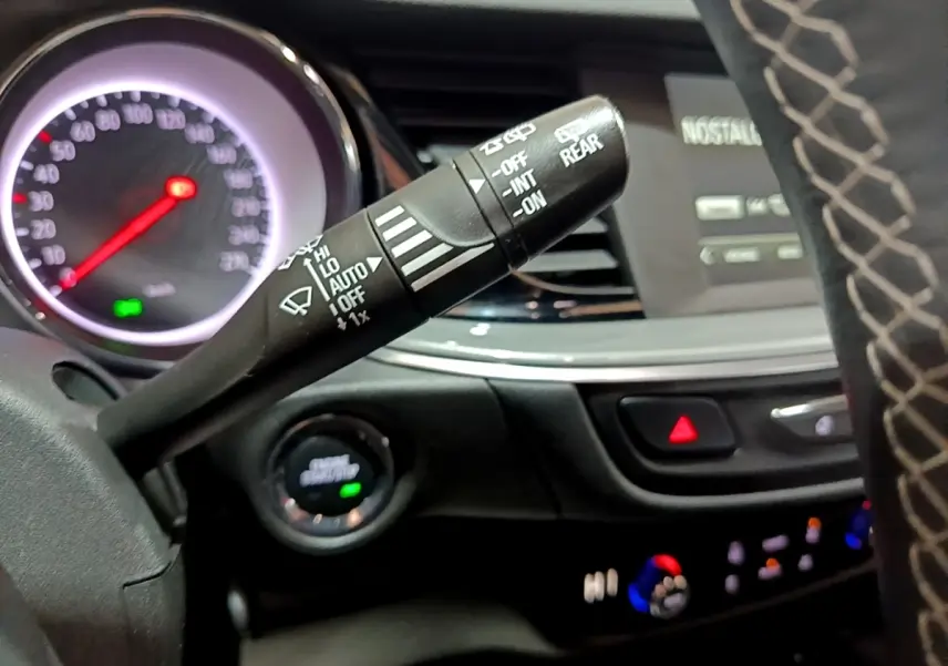 Gros plan sur la commande d’essuie-glace à gauche du volant dans l’habitacle sombre d’une Opel Insignia rouge 2019.