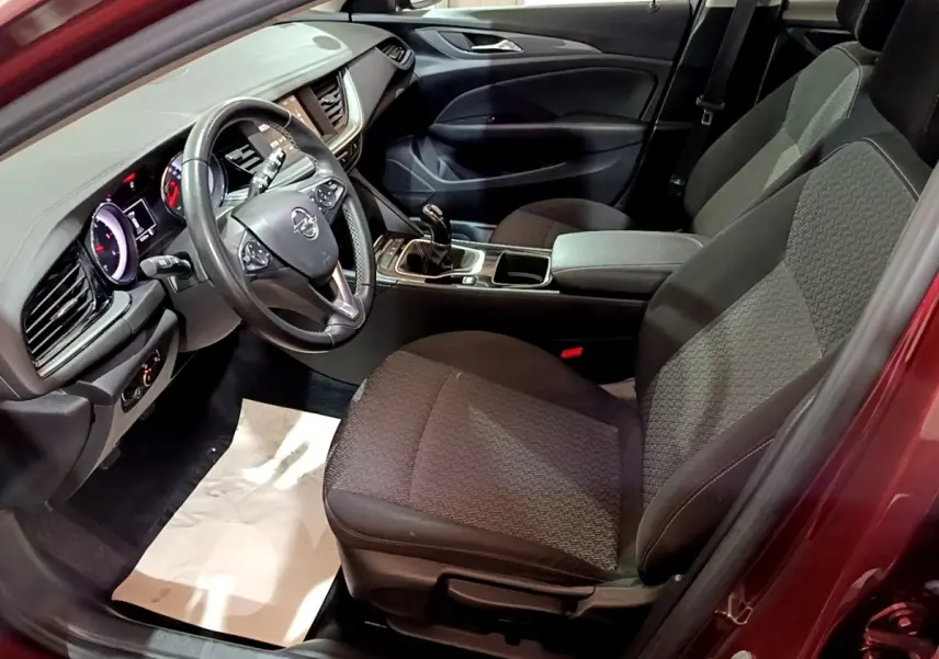 Intérieur avant droit de l’Opel Insignia rouge 2019, volant cuir multifonctions et console centrale avec boîte manuelle.