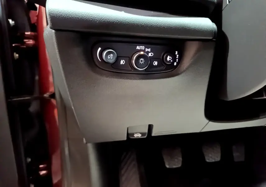 Détail du panneau de commande des phares côté gauche dans l’habitacle d’une Opel Insignia rouge de 2019.
