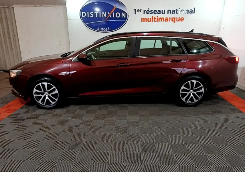 Opel Insignia break rouge vue de profil côté gauche dans un garage avec sol à damier gris et orange.