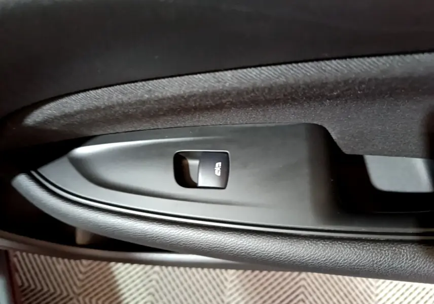 Gros plan sur le bouton de verrouillage centralisé noir sur la porte intérieure côté gauche de l’Opel Insignia rouge.