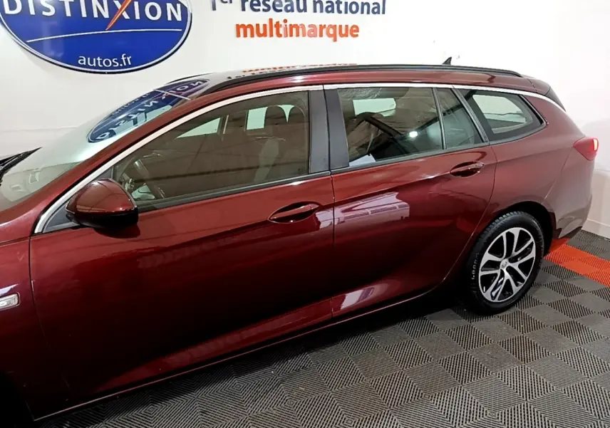 Vue latérale gauche d'une Opel Insignia break rouge 2019 avec jantes alliage et rétroviseur assorti.