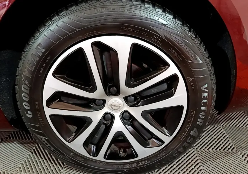 Gros plan sur la roue avant droite d’une Opel Insignia rouge, mettant en valeur la jante alliage bicolore et le pneu Goodyear.