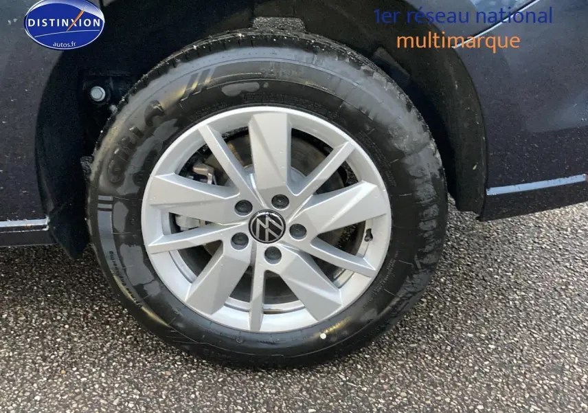 Gros plan sur la roue avant gauche d’un Volkswagen Caddy bleu métallisé avec jante alliage argentée.