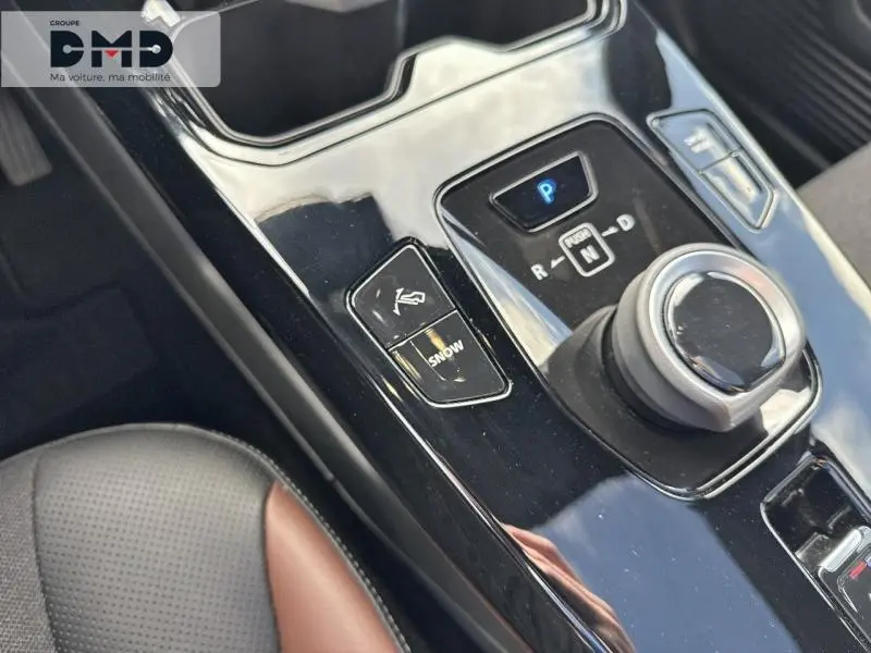 Gros plan sur la console centrale noire brillante du Suzuki Vitara électrique avec sélecteur rotatif et bouton mode Snow.