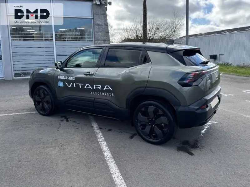 Suzuki Vitara électrique 2026 vert Land Breeze avec toit noir, vue 3/4 arrière droit, marquage latéral visible.