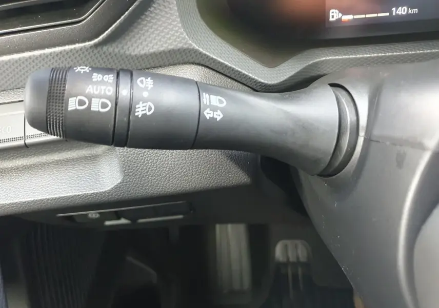Gros plan sur la commande des feux à gauche du volant dans l'habitacle du Dacia Dokker Van gris schiste.