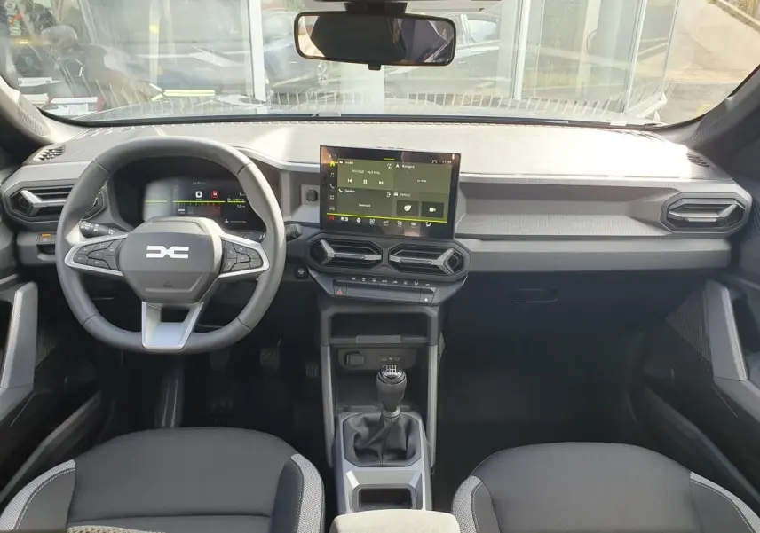 Vue intérieure frontale du tableau de bord gris et noir du Dacia Dokker Van 2026 avec écran tactile et volant multifonction.