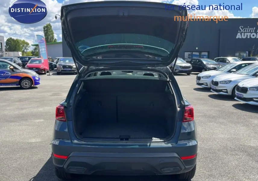 Vue arrière d'un SEAT Arona bleu Fjord avec coffre ouvert, montrant l'espace de chargement vide en extérieur.