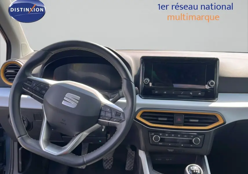 Vue intérieure du tableau de bord du SEAT Arona 2025, volant multifonction noir et console centrale avec écran tactile.