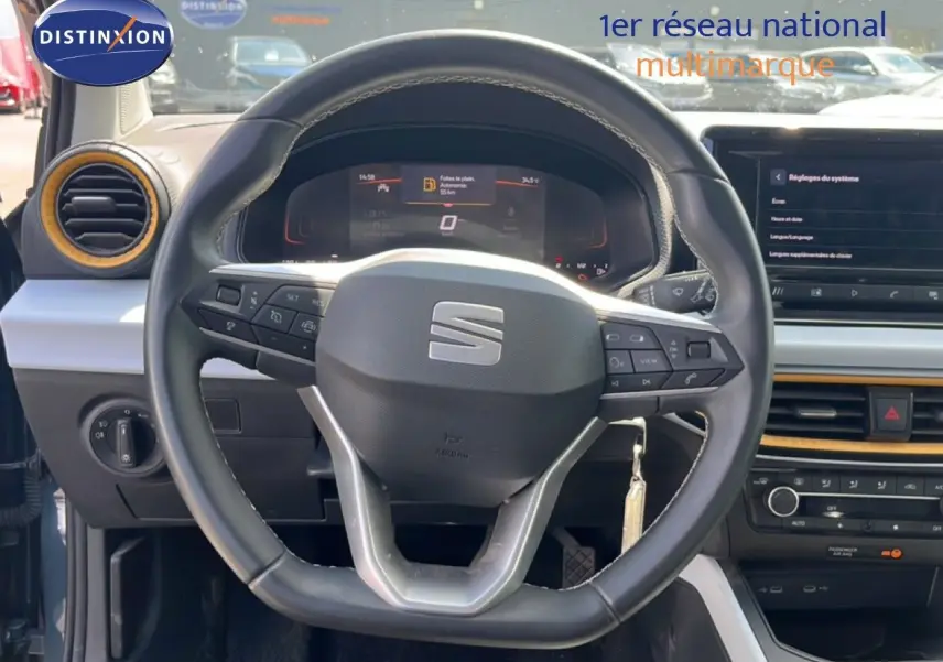Vue rapprochée du volant et tableau de bord de la SEAT Arona 2025, intérieur gris avec inserts jaunes.