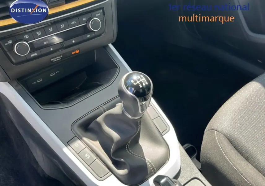 Gros plan sur la console centrale de la SEAT Arona 2025, boîte manuelle avec levier en cuir noir et tableau de bord gris.