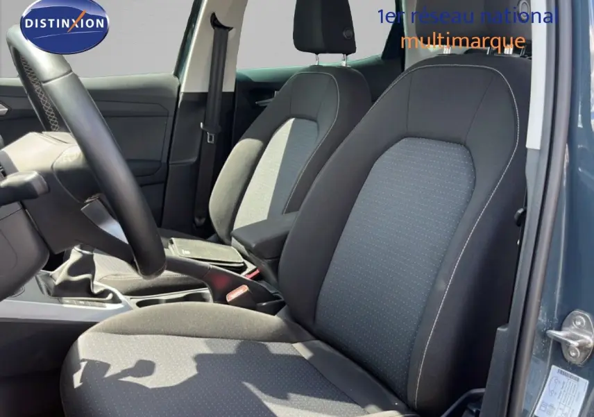 Vue intérieure côté conducteur du SEAT Arona 2025 bleu Fjord, montrant les sièges tissu gris-noir et la boîte manuelle.
