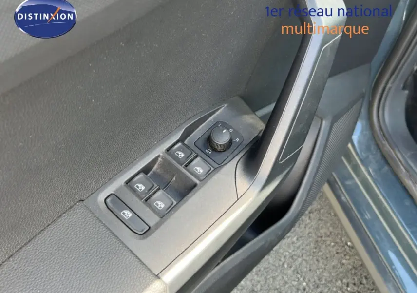 Gros plan sur les commandes des vitres et rétroviseurs côté conducteur d'une SEAT Arona bleu Fjord 2025.