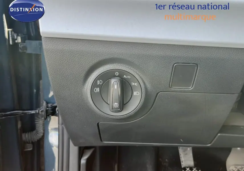 Gros plan sur le bouton de commande des phares côté gauche dans un SEAT Arona bleu Fjord avec toit blanc.
