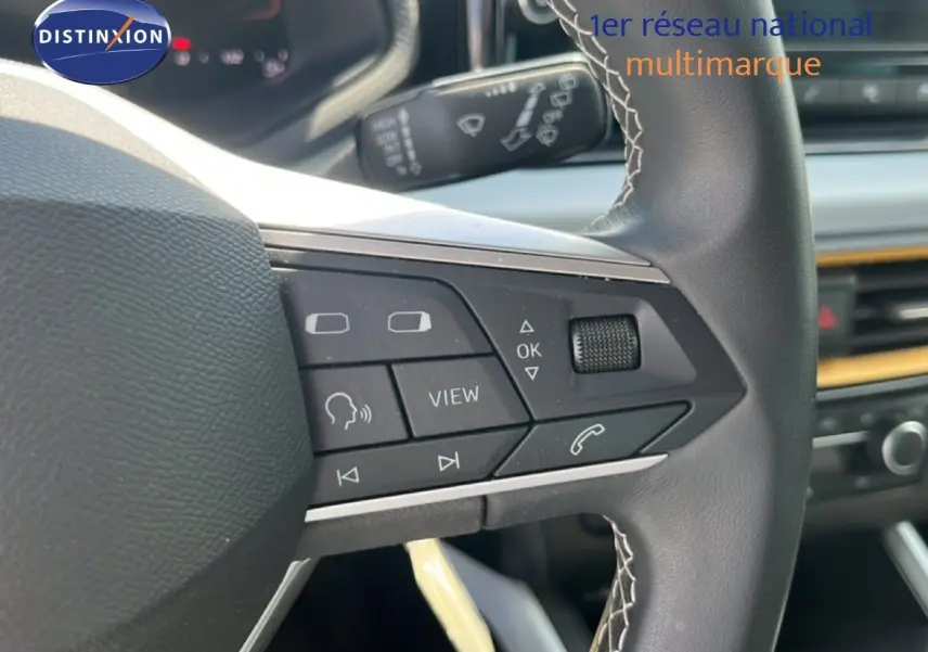 Gros plan sur le volant multifonction du SEAT Arona 2025, mettant en valeur les commandes intégrées et la finition noire.