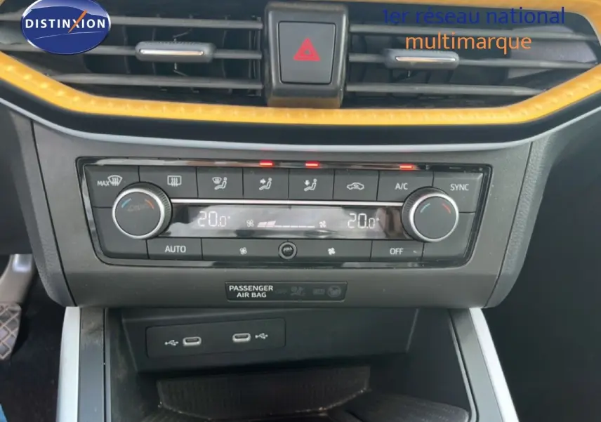 Vue rapprochée de la console centrale du SEAT Arona 2025, avec climatisation digitale et bordure jaune vif.