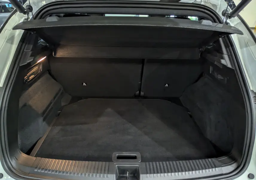 Coffre ouvert vu de l'arrière du Renault Austral blanc nacré avec intérieur noir et cache-bagages déployé.