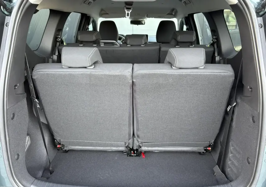 Vue arrière du coffre du Dacia Jogger Vert Cèdre 2024 avec sièges du troisième rang rabattus et tissu gris.