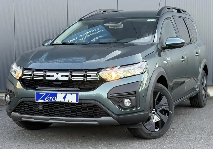 Vue 3/4 avant droite du Dacia Jogger Vert Cèdre 2024 avec signature lumineuse LED et barres de toit longitudinales.