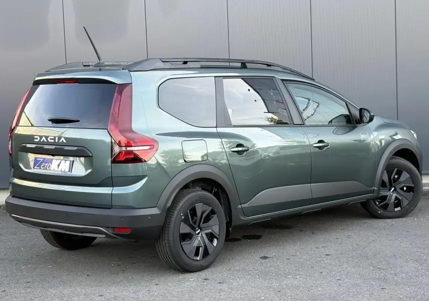 Vue 3/4 arrière droite d'un Dacia Jogger Vert Cèdre avec barres de toit et jantes noires modernes.