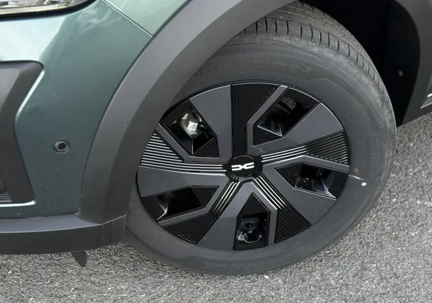 Gros plan sur la roue avant gauche du Dacia Jogger Vert Cèdre 2024 avec jante noire au design géométrique.