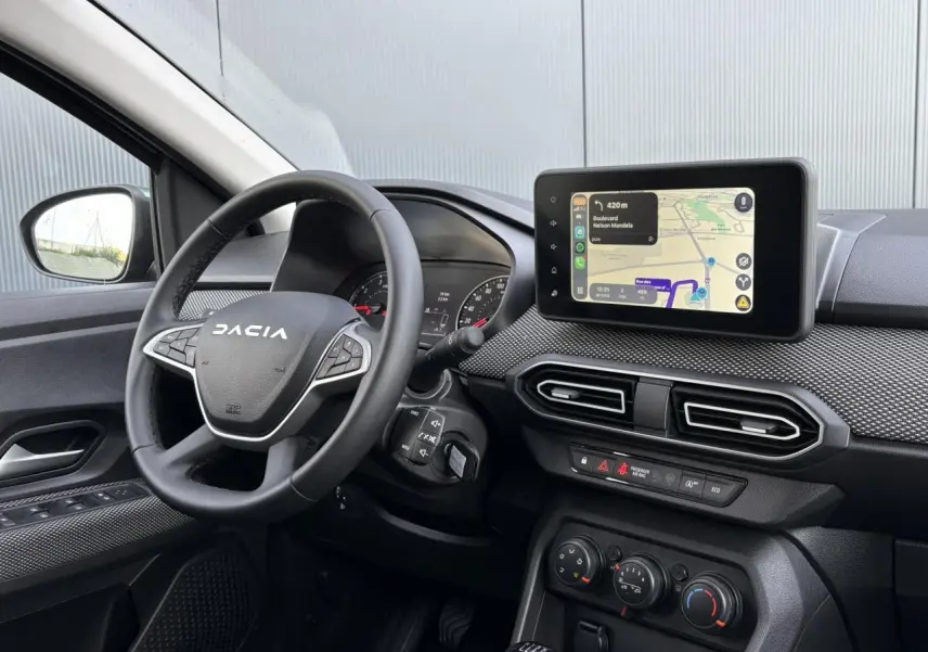 Vue intérieure du tableau de bord et volant Dacia Jogger avec écran tactile GPS et commandes au volant visibles.