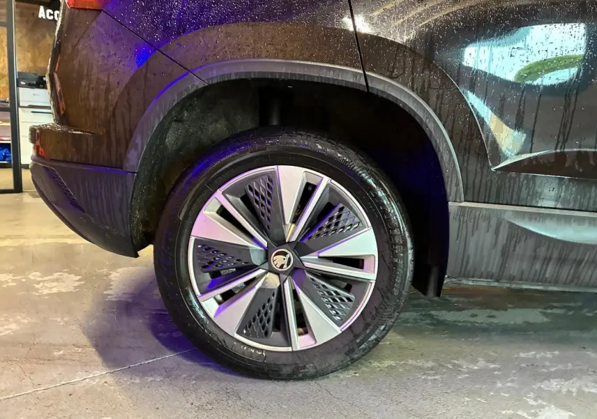 Gros plan sur la roue arrière gauche d’un SKODA KAROQ noir 2023, soulignant la jante au design moderne et le passage de roue.