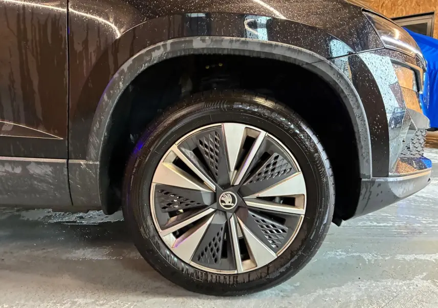 Gros plan sur la roue avant gauche d’un Skoda Karoq noir 2023, mettant en valeur la jante au design moderne bicolore.
