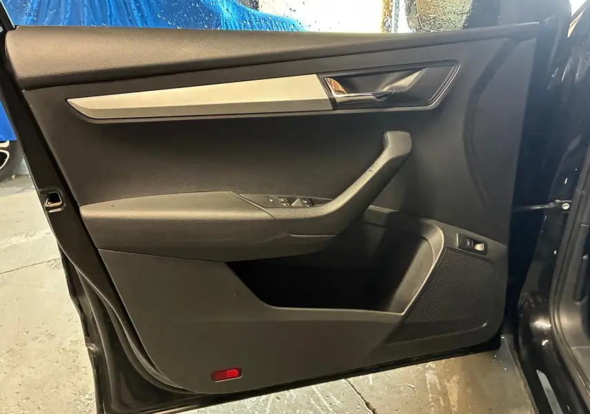 Vue intérieure de la porte avant gauche noire du Skoda Karoq 2023 avec garniture tissu et insert argenté.