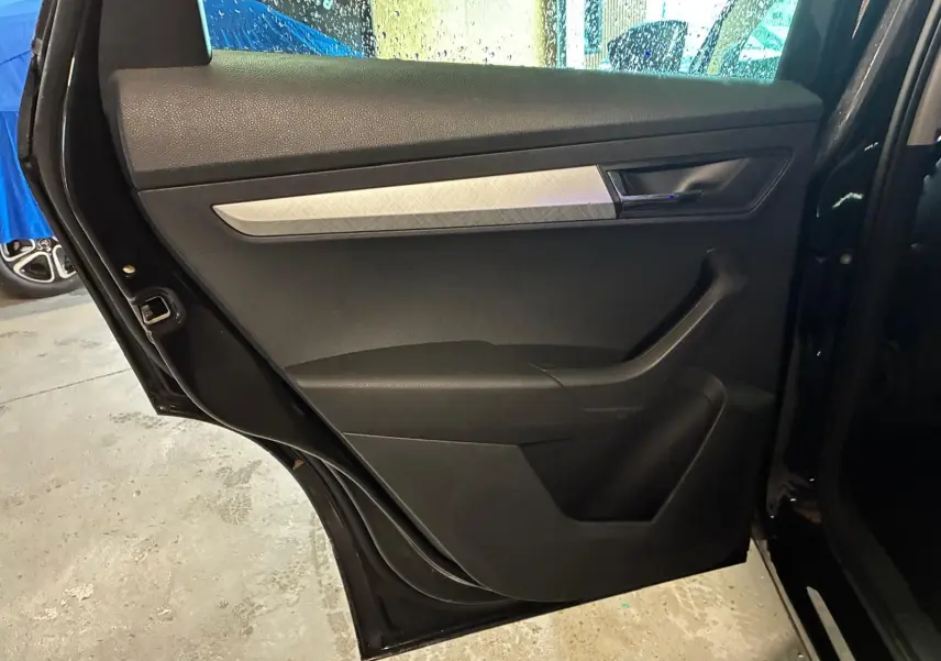 Vue rapprochée de la porte arrière gauche noire du Skoda Karoq 2023 avec garniture intérieure noire et insert argenté.