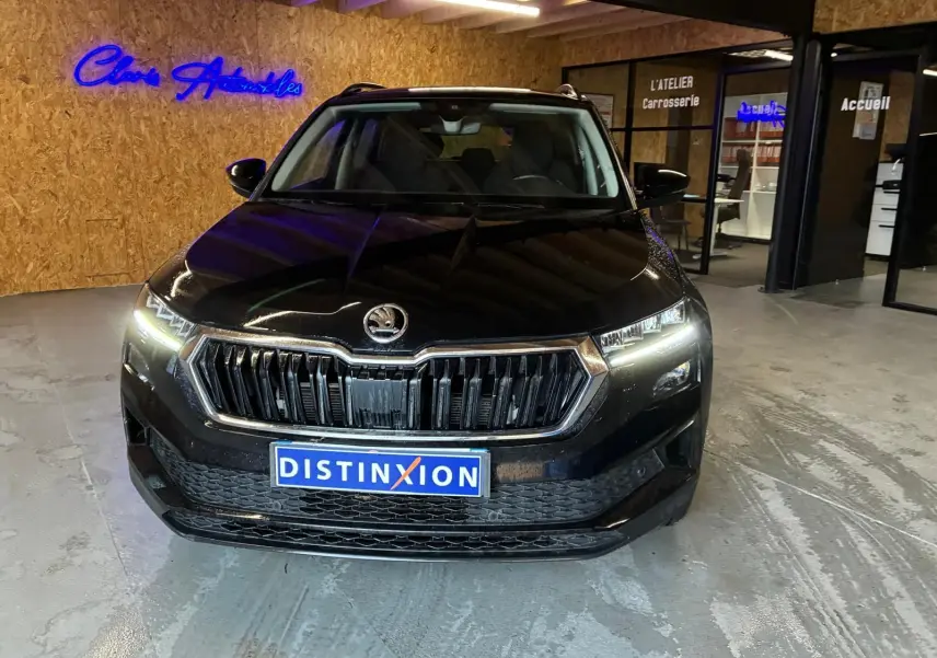 Vue de face d’un Skoda Karoq noir 2023 avec phares allumés dans un showroom intérieur.