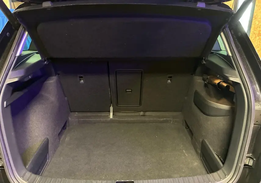 Coffre ouvert vu de l'arrière d'un Skoda Karoq noir 2023, intérieur tissu noir et espace de chargement vide.