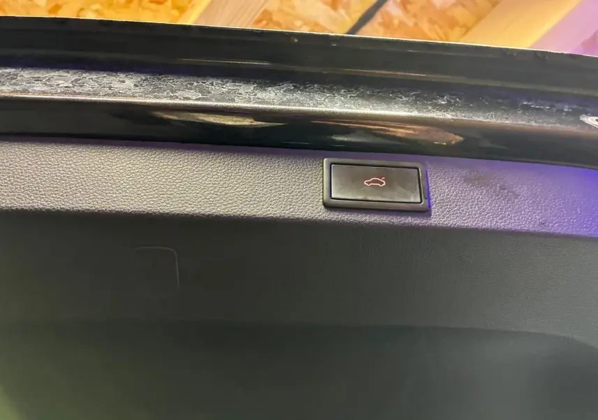Bouton d'ouverture électrique du coffre sur la partie intérieure de la malle arrière noire d'un Skoda Karoq 2023.