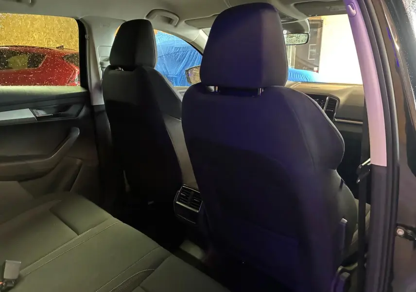 Vue intérieure arrière côté droit du Skoda Karoq noir 2023, mettant en valeur les sièges en tissu noir et les aérateurs arrière.