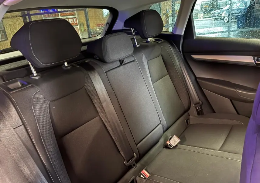 Vue intérieure de la banquette arrière noire en tissu du Skoda Karoq 2023, avec appuie-têtes et ceintures visibles.