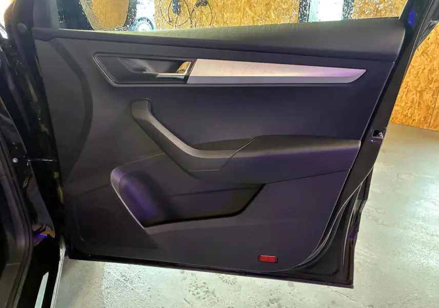 Vue intérieure de la porte avant gauche noire du Skoda Karoq 2023, avec garniture tissu et insert argenté.