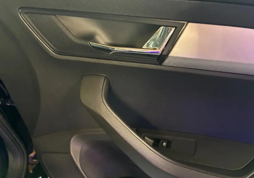 Gros plan sur la porte intérieure côté gauche du Skoda Karoq noir, avec poignée et commande de vitre visible.