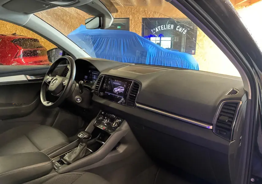 Intérieur noir du Skoda Karoq 2023, vue côté conducteur montrant tableau de bord et console centrale avec écran tactile.
