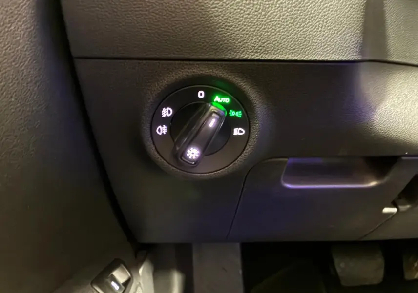 Gros plan sur le sélecteur de phares allumés en mode automatique dans l’habitacle noir du Skoda Karoq 2023.
