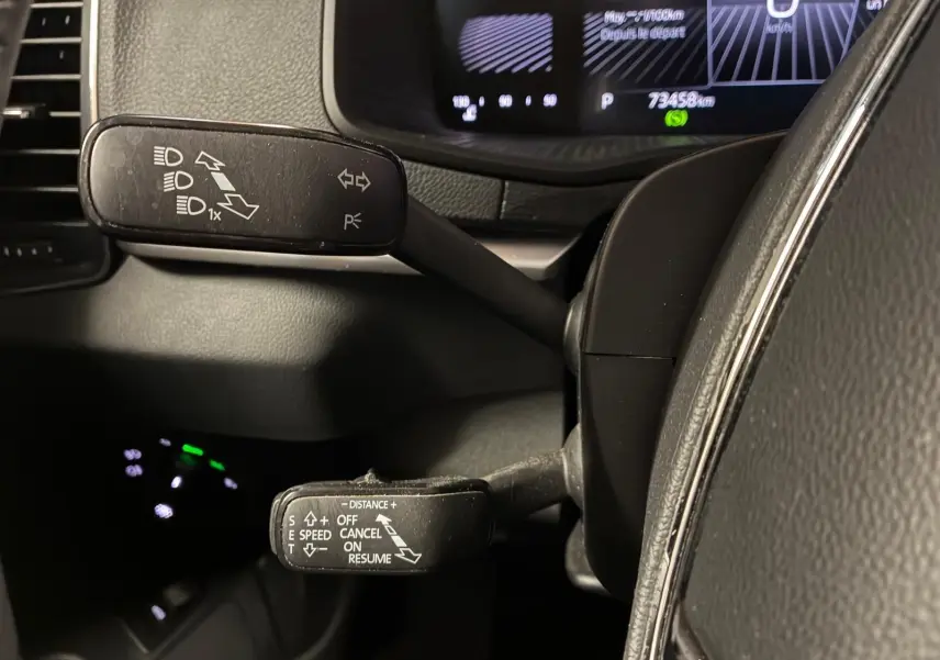 Gros plan sur les commandes au volant du Skoda Karoq noir 2023, avec leviers de clignotants et régulateur de vitesse.