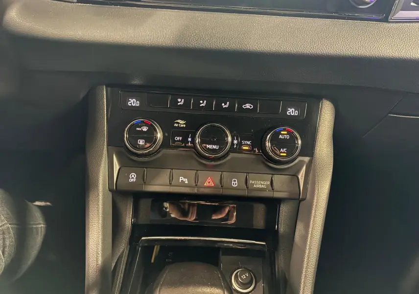 Vue rapprochée du tableau de bord noir du Skoda Karoq 2023, mettant en valeur la console de climatisation automatique et les commandes.