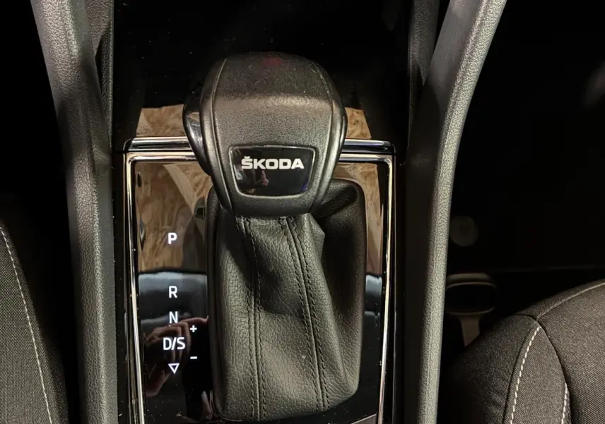 Gros plan sur la console centrale noire du Skoda Karoq 2023, mettant en valeur le levier de vitesses automatique marqué ŠKODA.