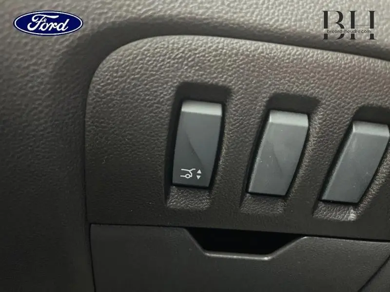 Gros plan sur les commandes noires du tableau de bord d'un Renault Espace noir étoilé, bouton d'ouverture du coffre visible.