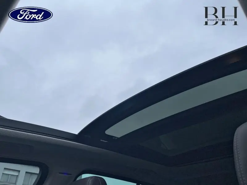 Vue intérieure du toit panoramique en verre du Renault Espace noir étoilé, avec ciel nuageux en arrière-plan.