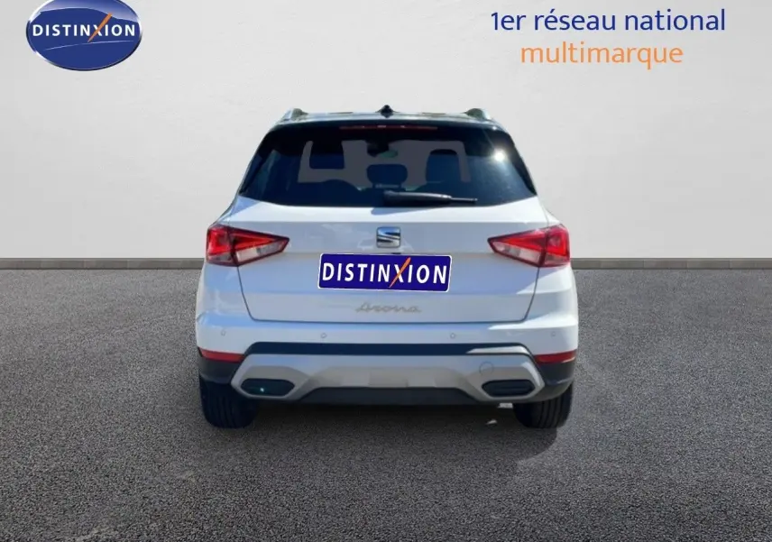 Vue arrière d’un SEAT Arona blanc Nevada avec toit noir, feux arrière anguleux et double sortie d’échappement intégrée.