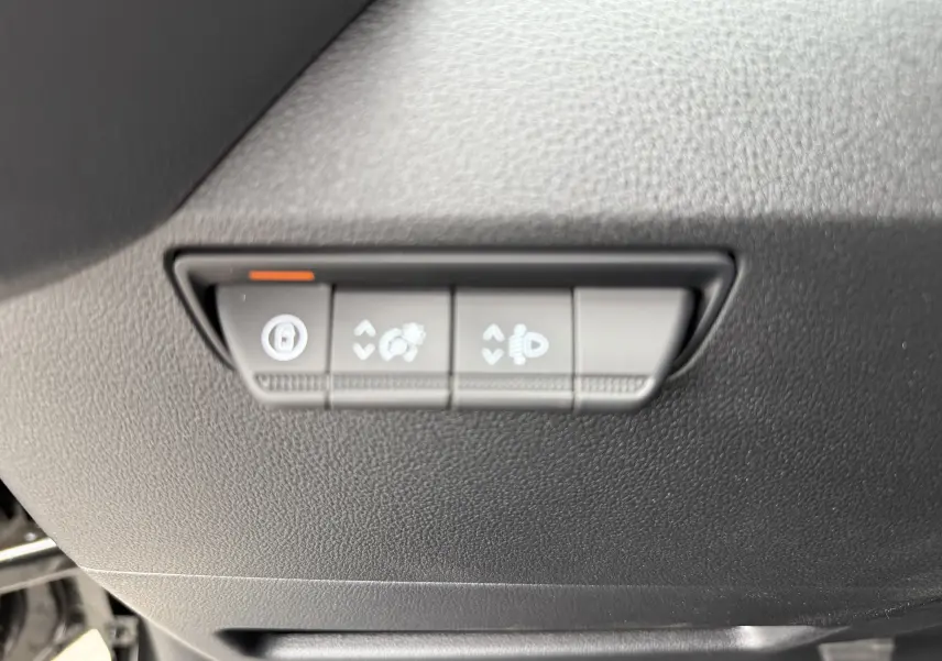 Gros plan sur les commandes de réglage des phares et du tableau de bord du Renault Master noir nacré 2024.