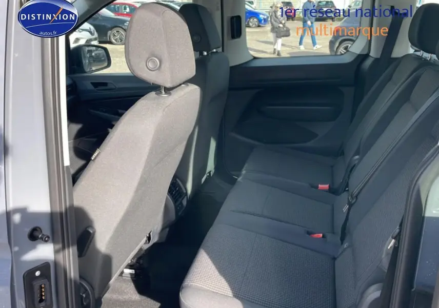 Vue intérieure côté droit du Volkswagen Caddy 2025 gris pur, montrant la banquette arrière trois places en tissu noir titane.