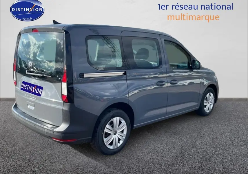 Volkswagen Caddy gris pur vue 3/4 arrière droit avec vitres teintées et barres de toit visibles.