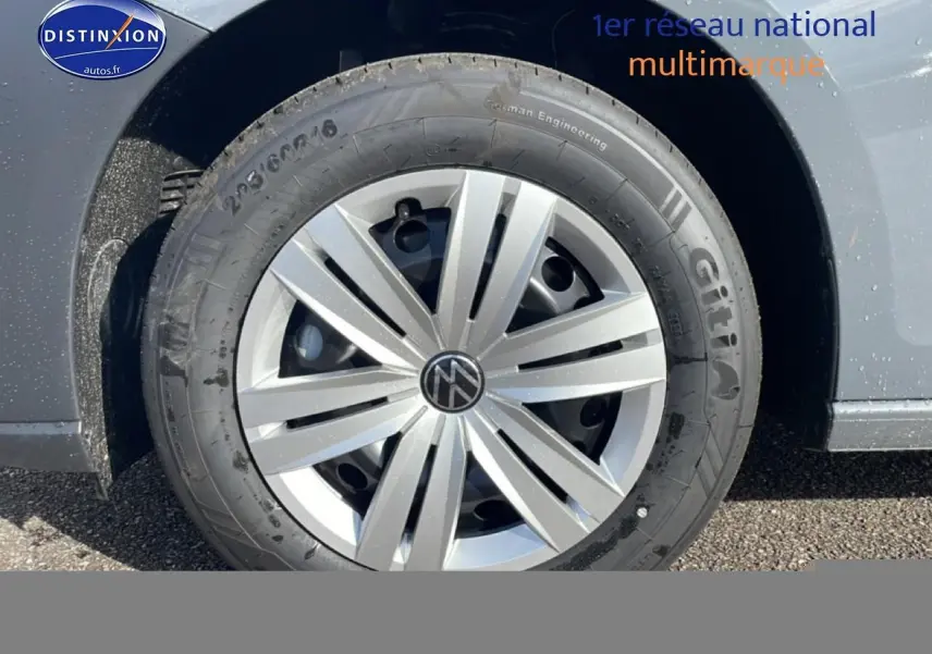 Gros plan sur la roue avant droite d’un Volkswagen Caddy gris pur avec jante argentée et logo VW central.